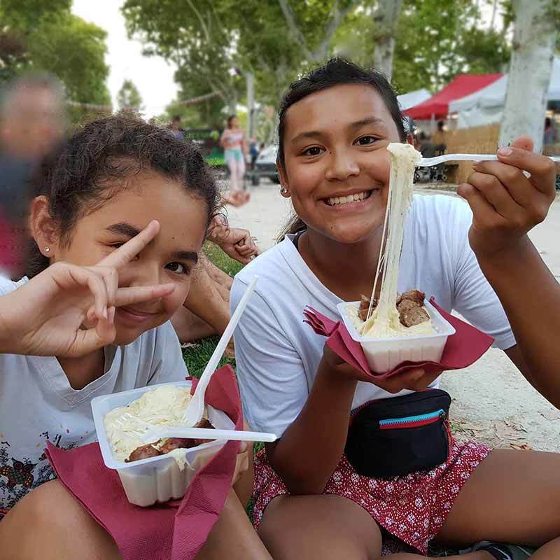 Aligot is a popular food in southern France and at Christmas markets in southern France Photo of daughter and cousin eating Aligot at a fair in Montpellier