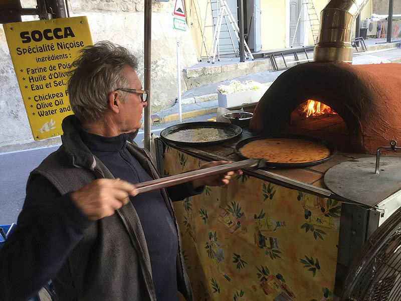 Socca, is a traditional niçoise dish from nice France photo of vendor cooking Socca, a traditional niçoise dish from nice France